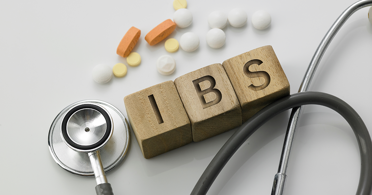 Block letters spelling out IBS with pills and a  stethoscope