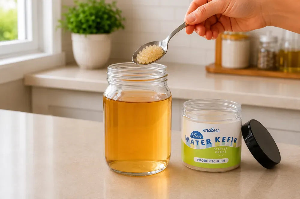 Amber water kefir grains being added to cooled sugar water in a quart jar