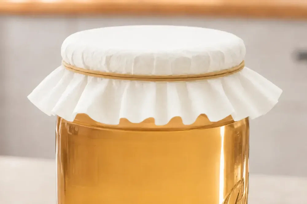 Quart jar of water kefir covered with butter muslin and a rubber band, fermenting on a counter